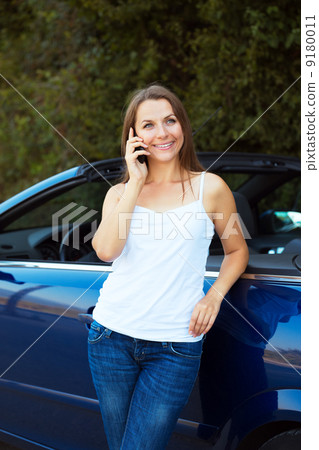 Smiling woman talking on phone in a cabriolet car 9180011