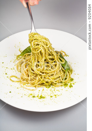 eating spaghetti mixed with fresh pesto 9204084