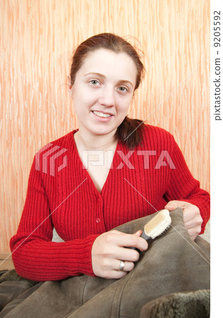 Woman cleaning a sheepskin with whisk broom 9205592