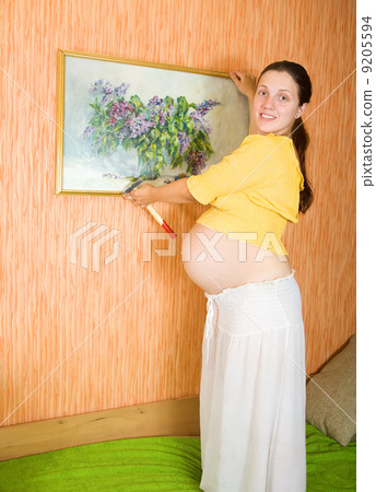 pregnant woman decorating room with picture 9205594