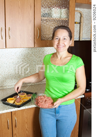 Woman making stuffed vegetable marrow in her kitchen 9206024
