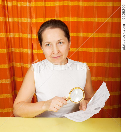 mature woman looking at utility bills 9206203