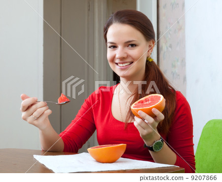 woman in red eats grapefruit at home 9207866