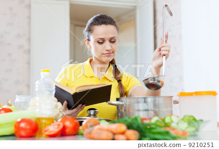 woman cooking food with book 9210251