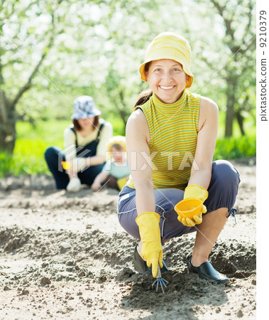 women and kid sows seeds in soil 9210379