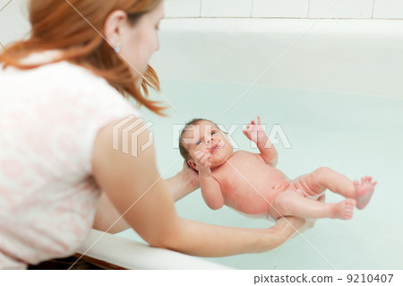 Mother bathes newborn baby 9210407