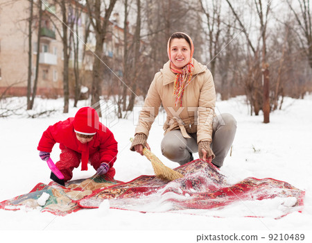 woman with child cleans rug with snow 9210489
