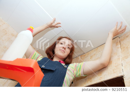 woman glues ceiling tile at home 9210551