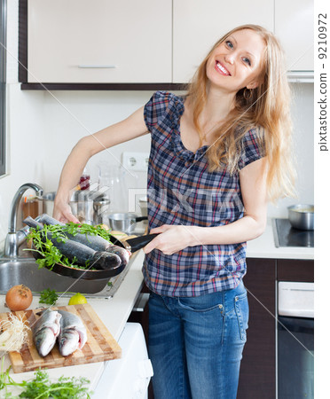 Positive girl with raw fish in frying pan Positive girl with raw fish in frying pan 9210972