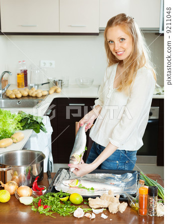 Cheeful woman cooking full fish Cheeful woman cooking full fish 9211048