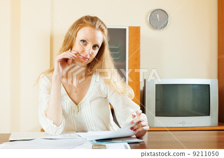 blonde woman looking financial documents at table blonde woman looking financial documents at table 9211050