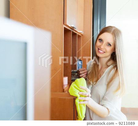 Happy blonde long-haired girl wiping the dust Happy blonde long-haired girl wiping the dust 9211089