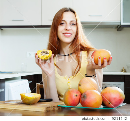 woman holding holding ripe mango at kitchen woman holding holding ripe mango at kitchen 9211342