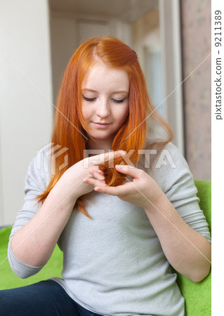 eenager looks at the tips of her hair 9211389