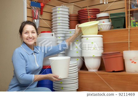 Mature woman chooses flowerpot 9211469