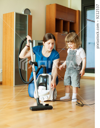 Woman teaches daughter to use the vacuum cleaner Woman teaches daughter to use the vacuum cleaner 9212537