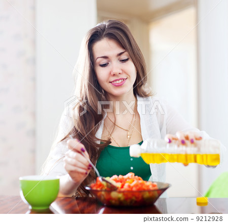 Woman pouring vegetable oil in to veggie salad Woman pouring vegetable oil in to veggie salad 9212928