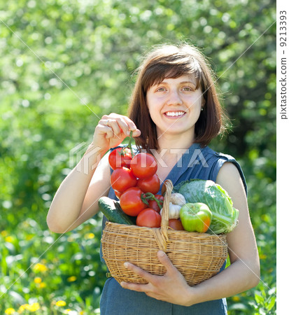 Happy woman with basket of harvested vegetables 9213393