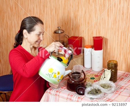 Mature woman brews herbs 9213897