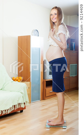 Happy pregnancy woman on bathroom scale Happy pregnancy woman on bathroom scale 9214409