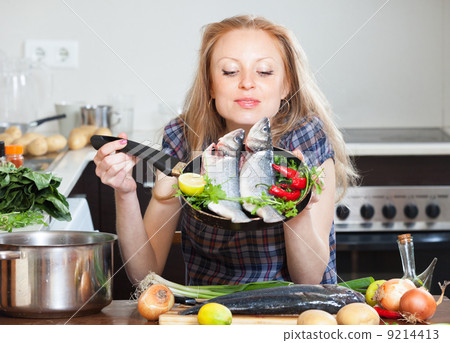 girl with raw seabass in frying pan girl with raw seabass in frying pan 9214413