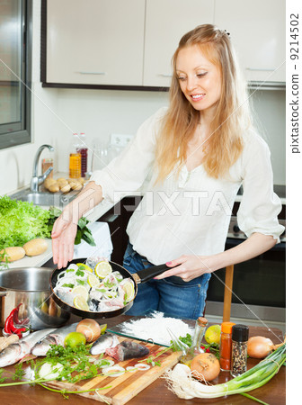 Positive woman cooking fish with lemon Positive woman cooking fish with lemon 9214502