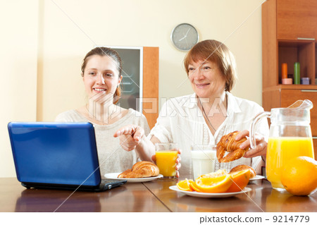 women looking e-mail in laptop during breakfast 9214779