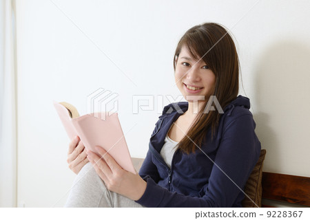 一個年輕的女人在床上聽音樂 9228367