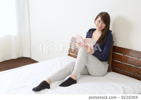 一個年輕的女人在床上聽音樂 一個年輕的女人在床上聽音樂 9228369
