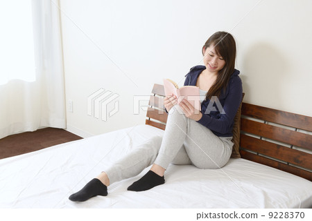 一個年輕的女人在床上聽音樂 一個年輕的女人在床上聽音樂 9228370