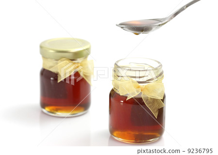 honey dripping from drizzler on top of jar, isolated on white ba 9236795