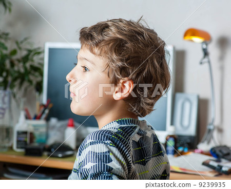 Side view of a little boy at table in the room Side view of a little boy at table in the room 9239935