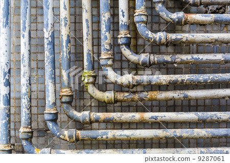 Series of parallel old pipes on wall 9287061