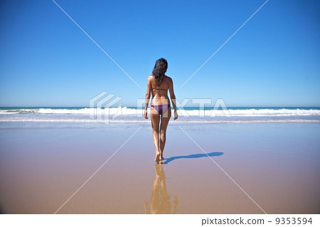 woman walking towards water at seashore 9353594