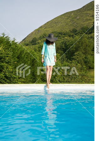 woman test water on swimming pool border 9354166