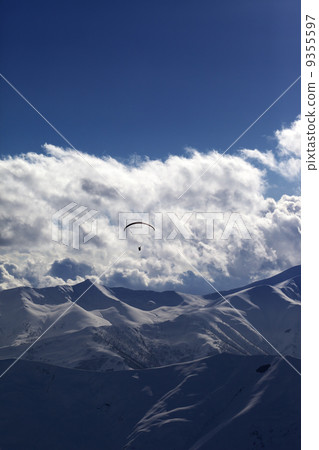 Winter mountain in evening and silhouette of parachutist 9355597