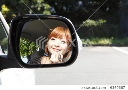 A woman making a make-up check with a side mirror 9369667