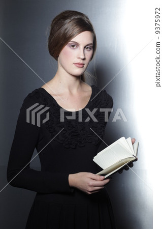woman in black dress holding book in her hands 9375972