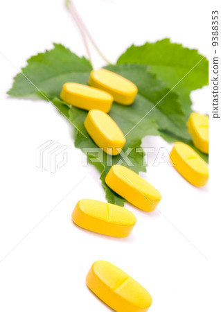 yellow vitamin pills over green leaves yellow vitamin pills over green leaves 9388353