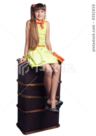 Little girl is sitting on old leather case 9391658