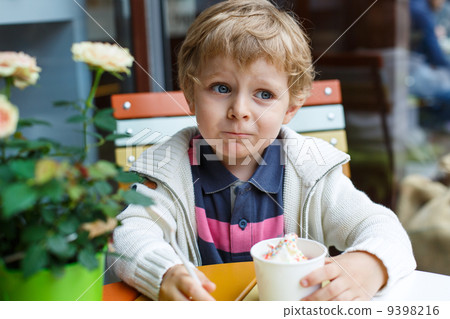 Adorable little boy eating frozen yoghurt ice cream in cafe Adorable little boy eating frozen yoghurt ice cream in cafe 9398216
