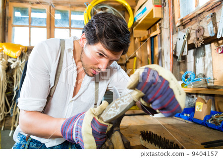 Young man sharpening tools in mountains hut 9404157