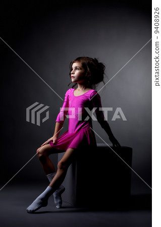 Pretty rhythmic gymnast sitting on cube in studio 9408926
