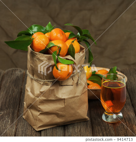 Fresh tangerines in recycle paper bag and glass of juice on wood 9414713