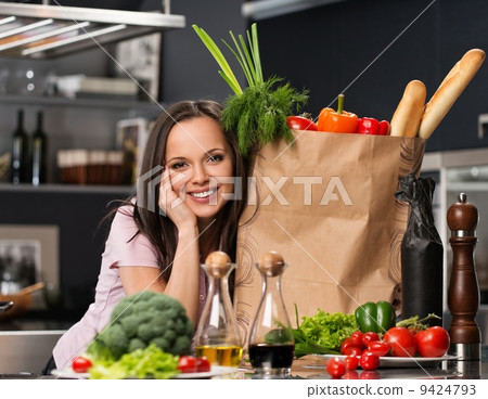 Young woman with grocery bag full of fresh vegetables on a modern kitchen 9424793