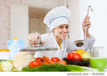 Happy cook in toque works at kitchen 9426983