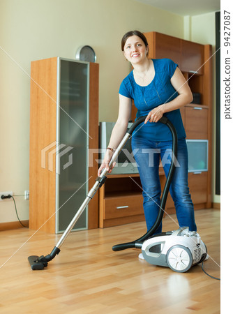 Stock Photo: Woman with vacuum cleaner on parquet