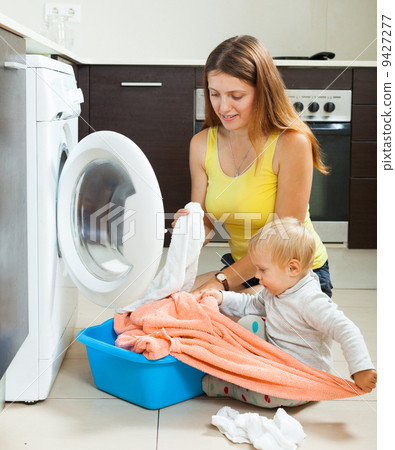 Family woman putting clothes in to washing machine Family woman putting clothes in to washing machine 9427277