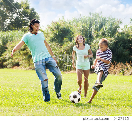 Middle-aged couple and teenager playing with soccer ball 9427515