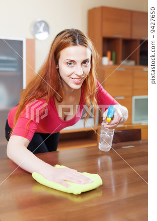 young woman dusting wooden table young woman dusting wooden table 9427650